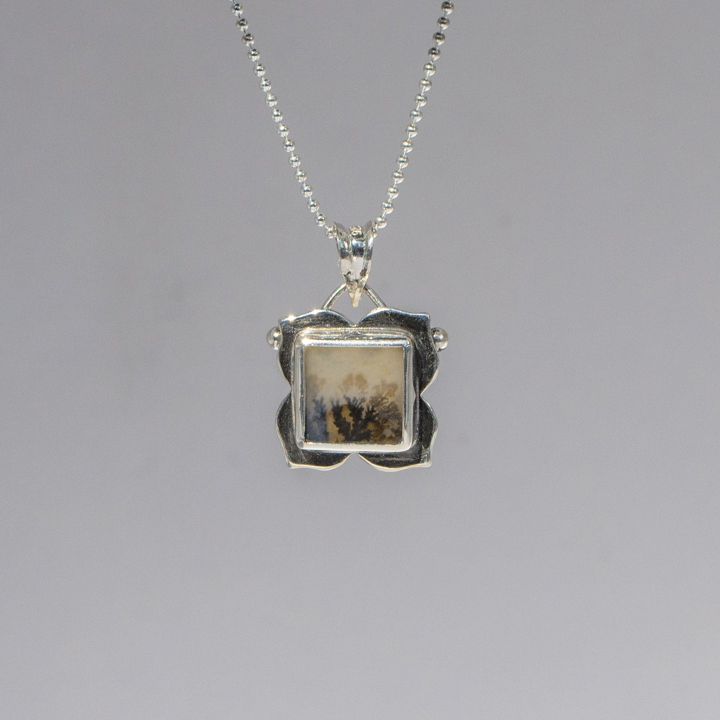 Silver pendant necklace on a gray background