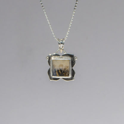 Silver pendant necklace on a gray background