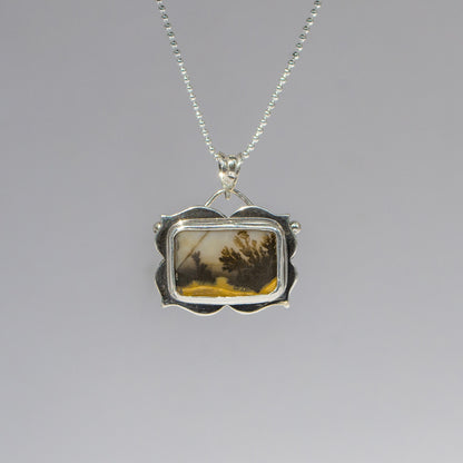 Silver pendant with a scenic design on a gray background
