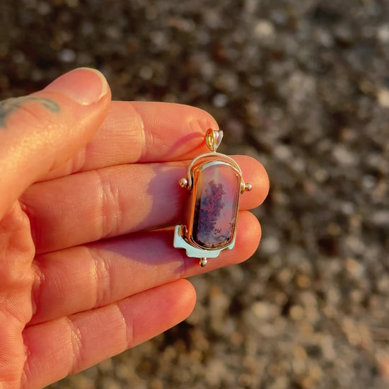 video showing gold charm shining in the afternoon sun being held by a hand.
