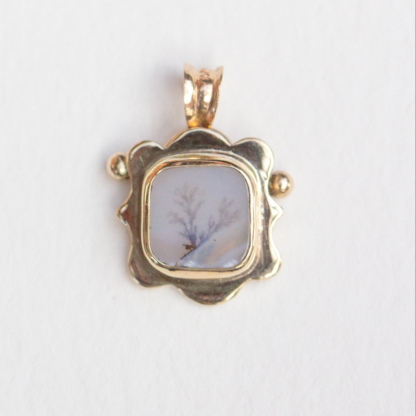 Gold pendant with a central stone on a white background