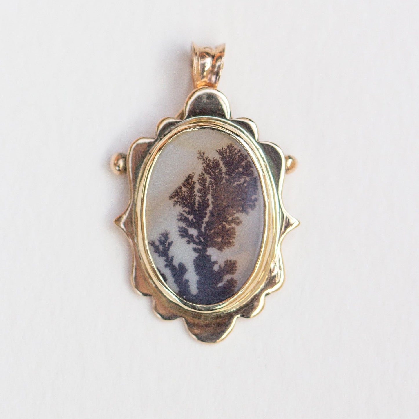 Gold pendant with a natural stone on a light gray background