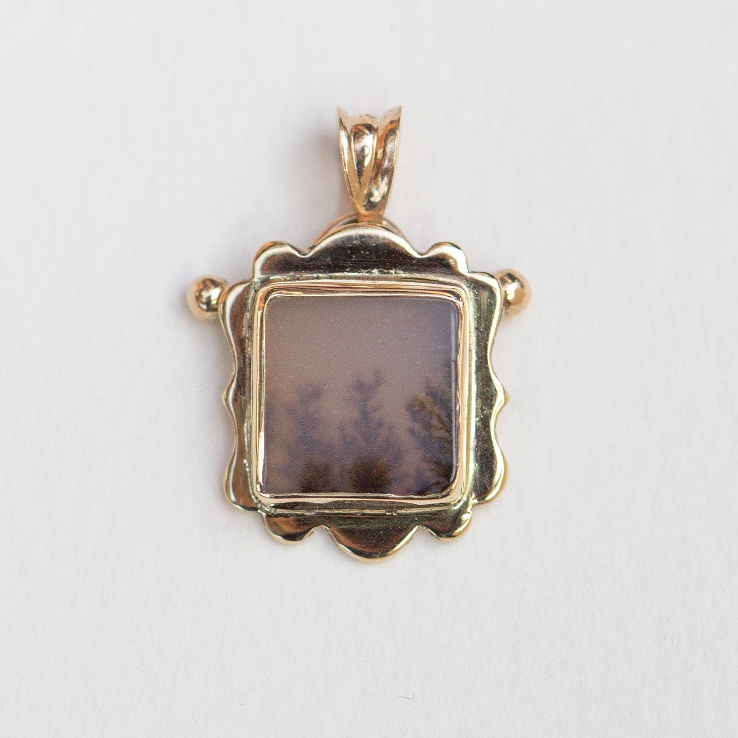 Gold pendant with a central stone on a white background