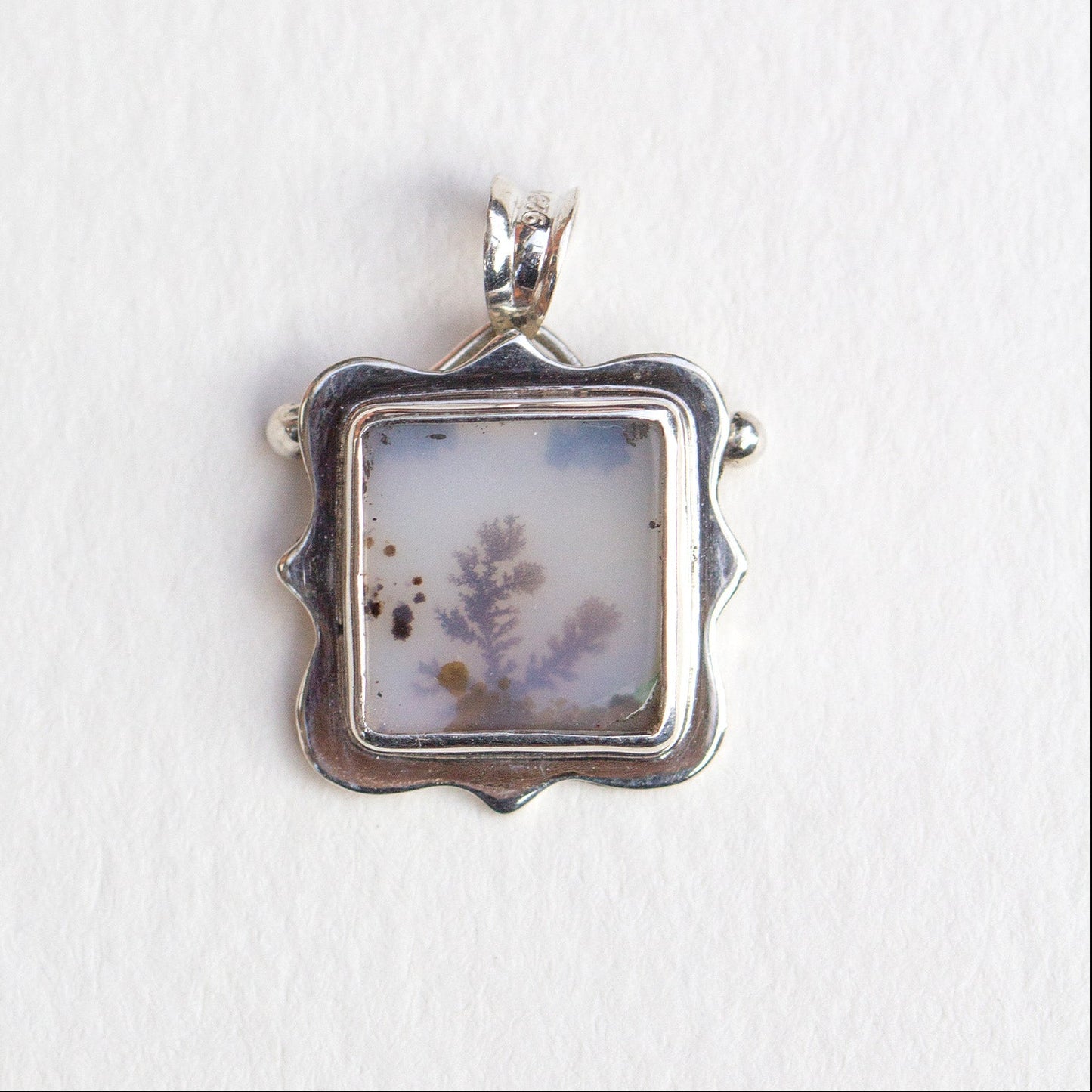 Silver pendant with a natural stone insert on a white background