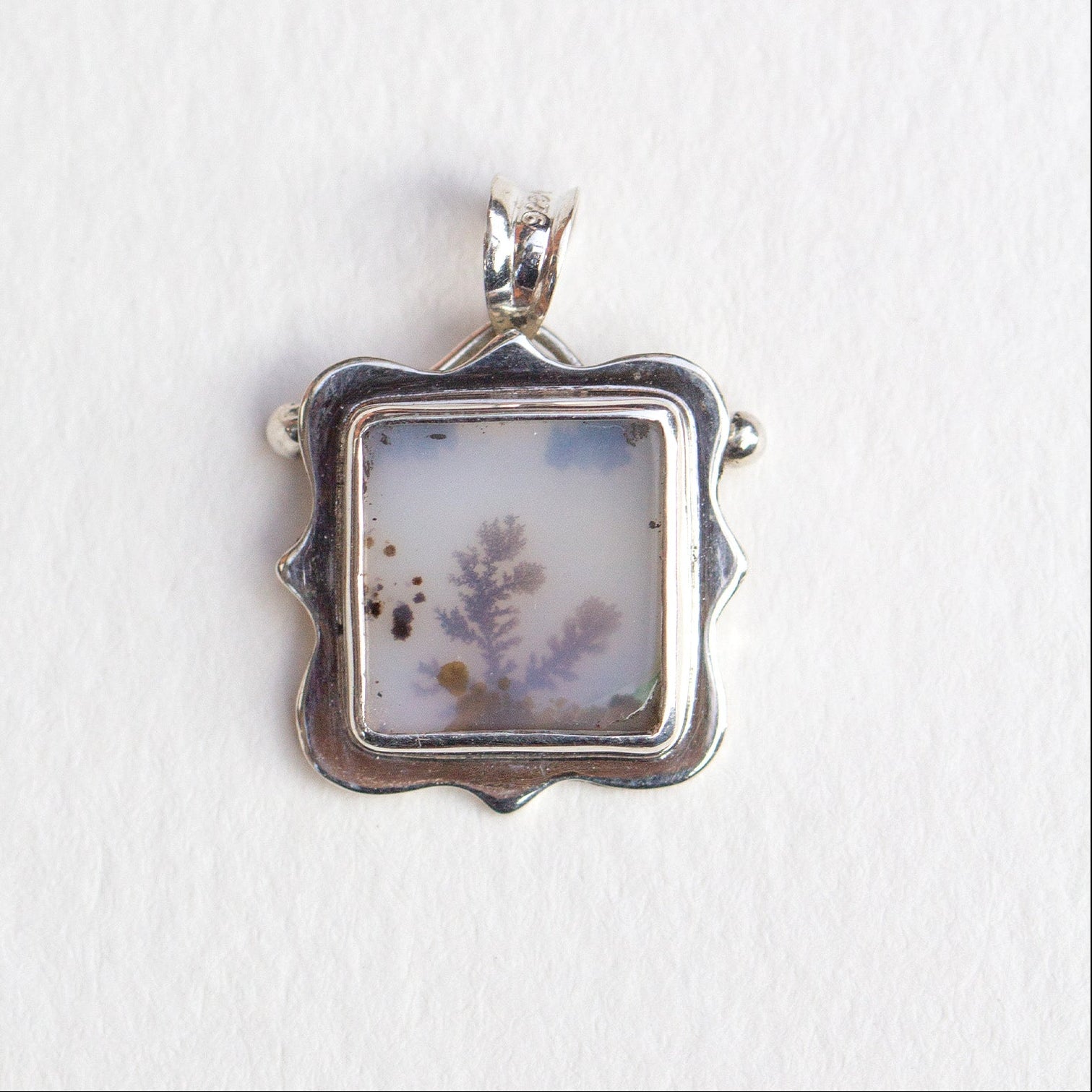 Silver pendant with a natural stone insert on a white background