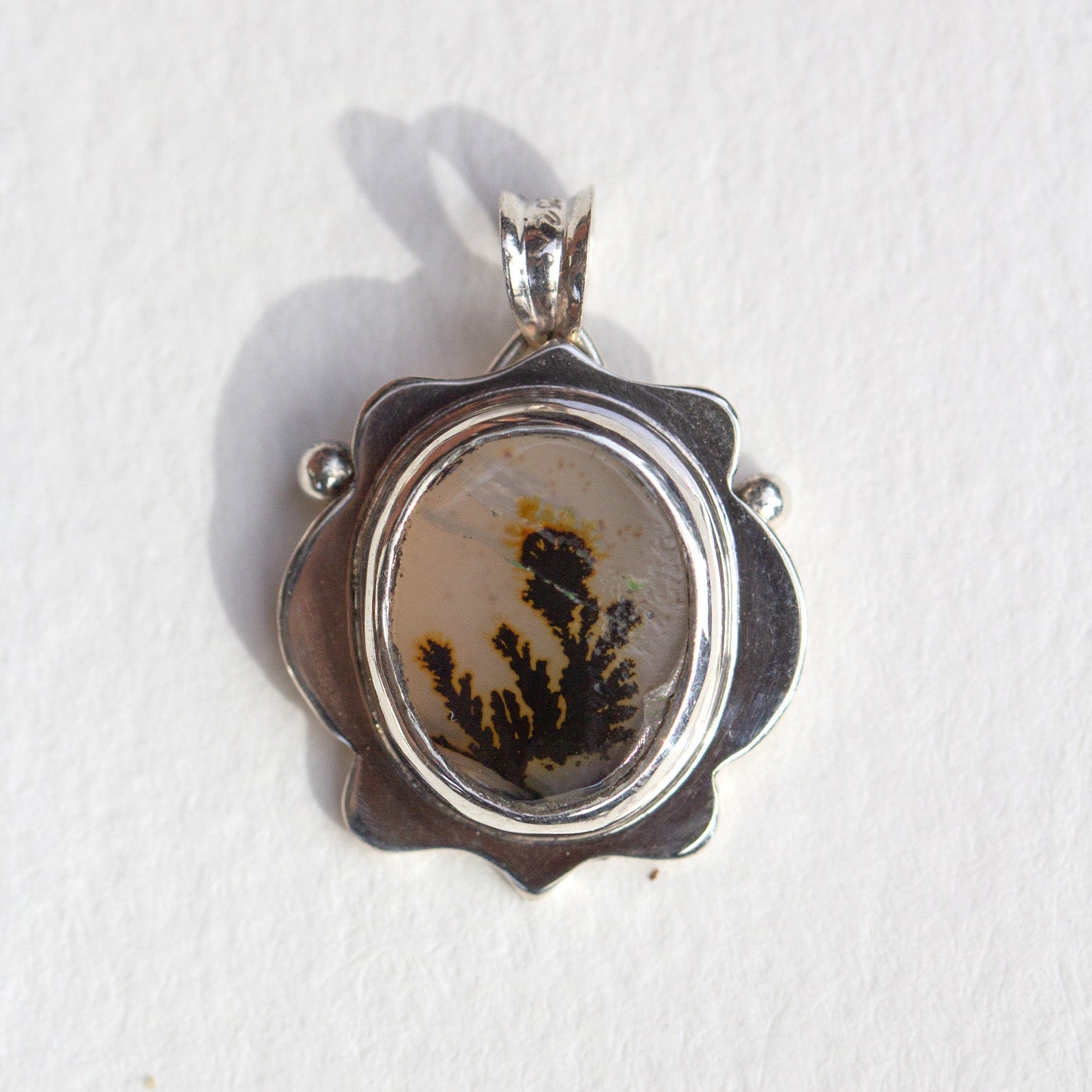 Silver pendant with a natural stone insert on a white background